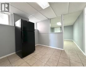 A black refrigerator in a room with a mirror on the wall.