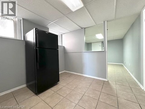 A black refrigerator in a room with a mirror on the wall.