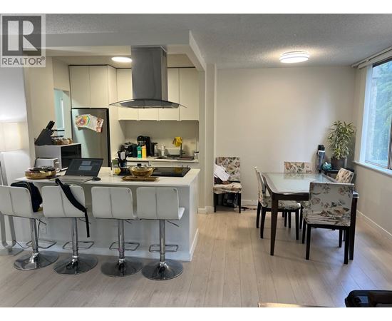 A kitchen with white chairs and a table.