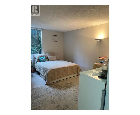 A bedroom with a bed, nightstand, and lamp.