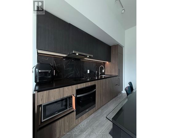A modern kitchen with dark wood cabinets and black countertops.