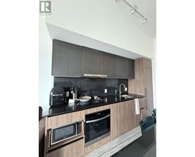 A modern kitchen with a black countertop and wooden cabinets.