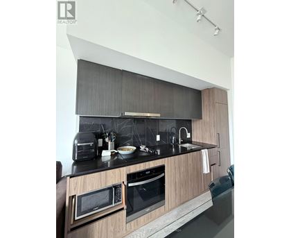 A modern kitchen with a black countertop and wooden cabinets.