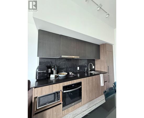 A modern kitchen with a black countertop and wooden cabinets.