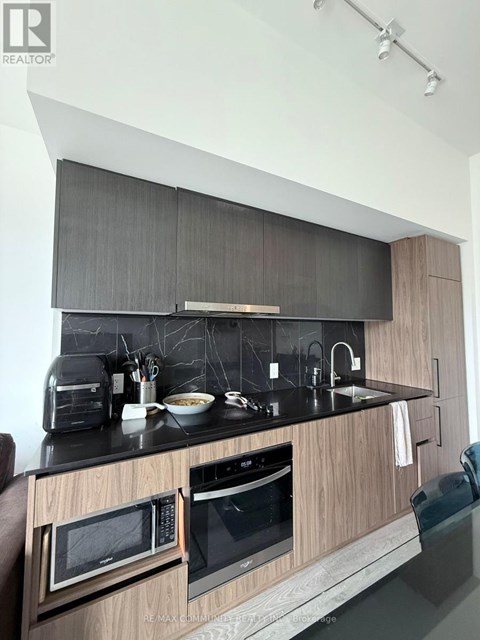 A modern kitchen with a black countertop and wooden cabinets.
