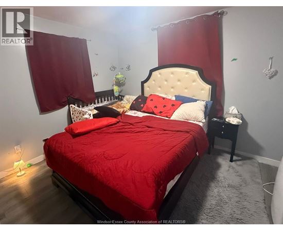 A bedroom with a red bedspread and a white headboard.
