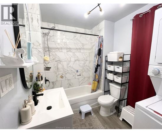 A white bathroom with a marble tile shower and a red shower curtain.