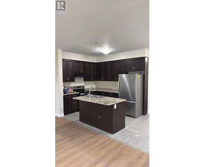 A kitchen with dark wood cabinets and a stainless steel refrigerator.