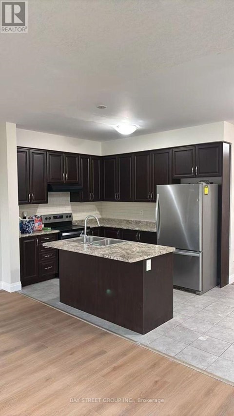 A kitchen with dark wood cabinets and a stainless steel refrigerator.