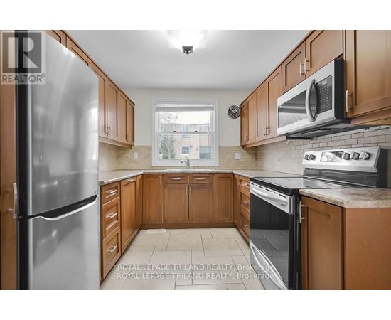 A kitchen with wooden cabinets and a stainless steel refrigerator.