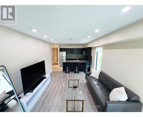 A modern living room with a flat screen TV and a black leather couch.