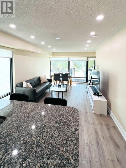 A living room with a black couch and a grey rug.