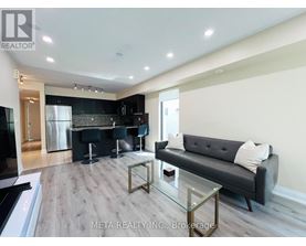 A modern kitchen with a black couch and a glass table.