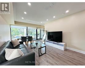 A living room with a black leather couch and a flat screen TV.