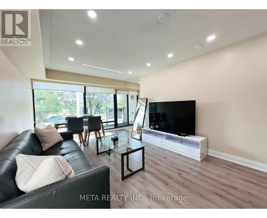 A living room with a black leather couch and a flat screen TV.