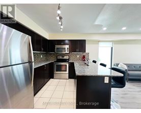 A kitchen with a stainless steel refrigerator and black cabinets.