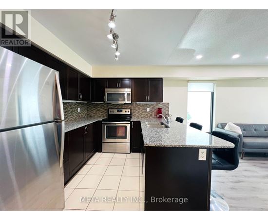 A kitchen with a stainless steel refrigerator and black cabinets.