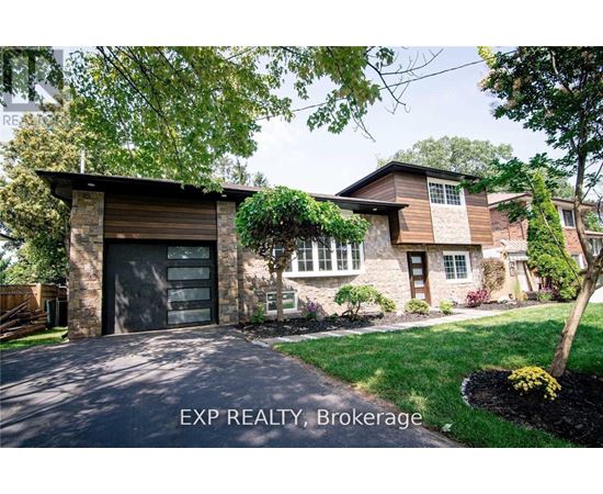 A house with a garage and a tree in front of it.