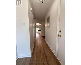 A long hallway with white walls and wood flooring.