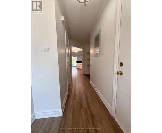 A long hallway with white walls and wood flooring.