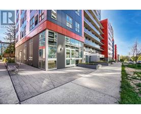 A modern multi-story building with a glass facade and a red stripe on the side.