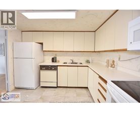 A kitchen with a white refrigerator, a sink, and a stove top oven.