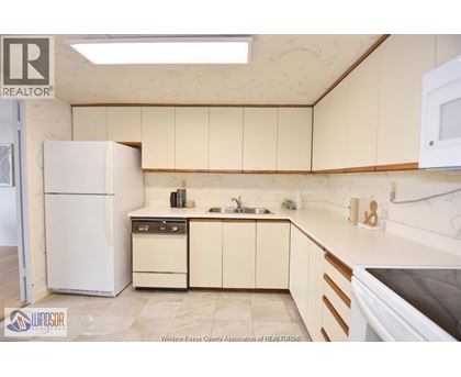 A kitchen with a white refrigerator, a sink, and a stove top oven.
