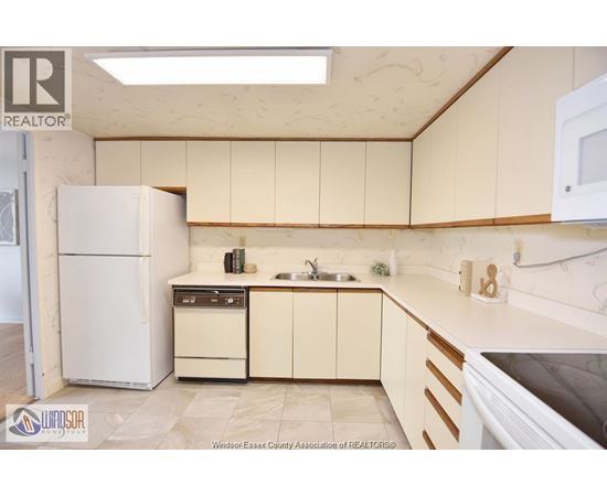 A kitchen with a white refrigerator, a sink, and a stove top oven.
