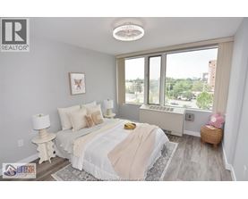 A bedroom with a large bed and a window overlooking a cityscape.