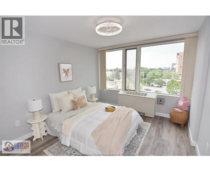 A bedroom with a large bed and a window overlooking a cityscape.