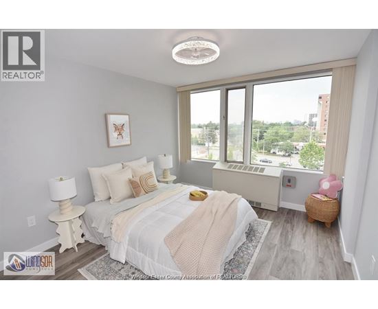 A bedroom with a large bed and a window overlooking a cityscape.