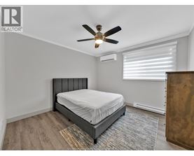 A bedroom with a bed, a ceiling fan, and a window with blinds.