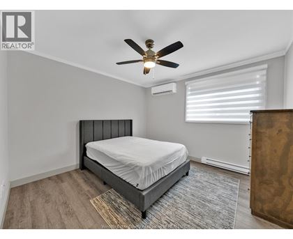 A bedroom with a bed, a ceiling fan, and a window with blinds.