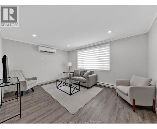 A living room with a white couch, a black chair, and a glass table.