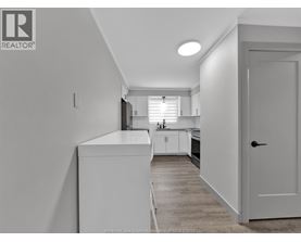 A kitchen with white cabinets and a white door.