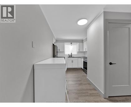 A kitchen with white cabinets and a white door.