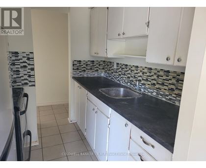 A kitchen with white cabinets and a black counter top.