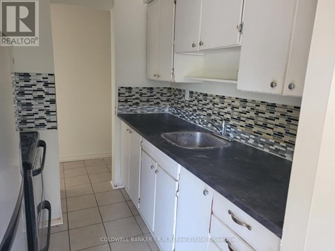 A kitchen with white cabinets and a black counter top.