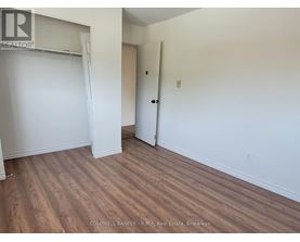 A room with wooden flooring and white walls, with a door and a closet.