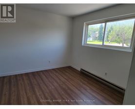 A room with a window and wooden flooring.