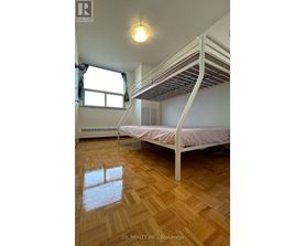 A bedroom with a white bunk bed and wooden flooring.