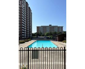 A pool in front of a tall brick building.