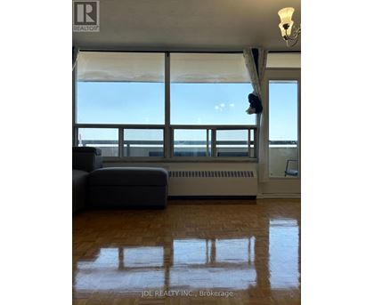 A living room with a couch and a large window overlooking the ocean.