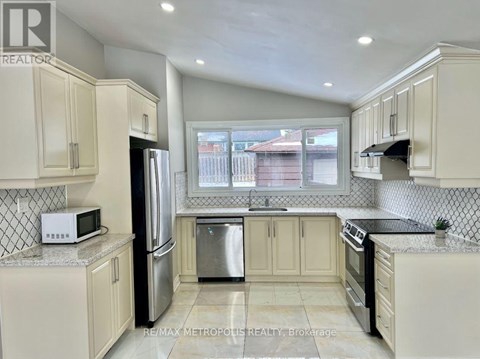 A kitchen with white cabinets and a black refrigerator.