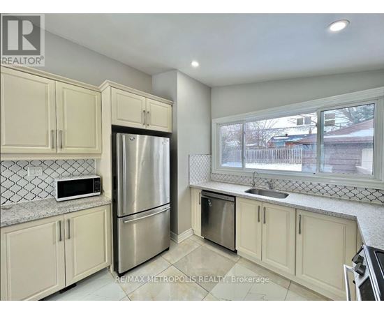 A kitchen with a refrigerator, microwave, and oven.
