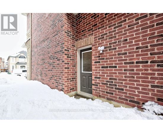 A red brick house with a grey door and snow on the ground.