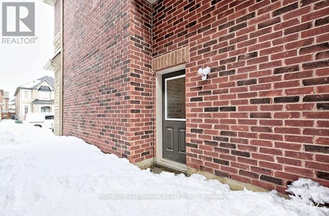 A red brick house with a grey door and snow on the ground.