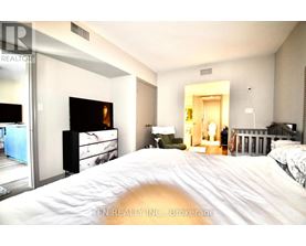 A bedroom with a large bed and a dresser with a mirror.