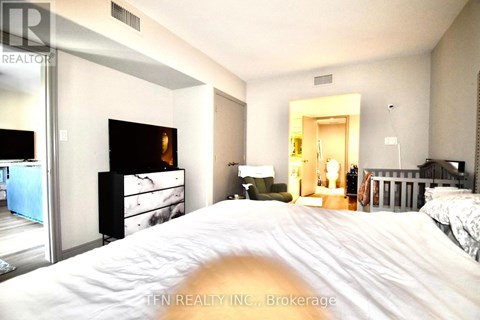 A bedroom with a large bed and a dresser with a mirror.