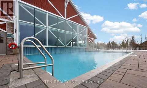 A pool area with a red building and a metal ladder.
